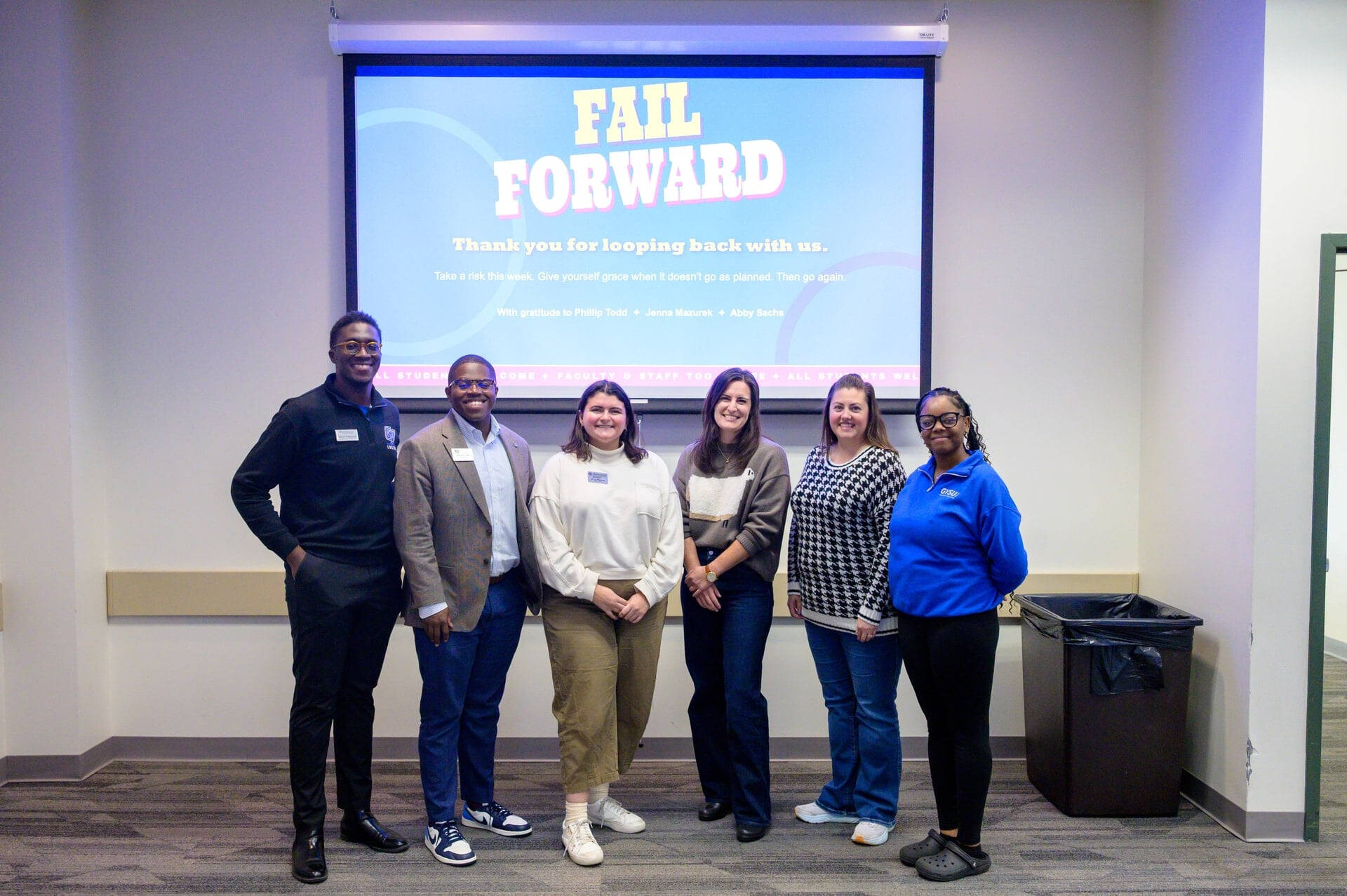 six people standing in front of screen that reads Fail Forward